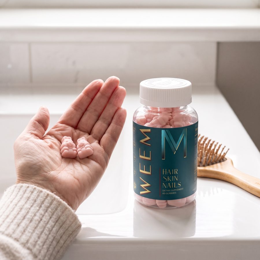 Two WEEM gummies in a palm next to the jar and a clean hairbrush