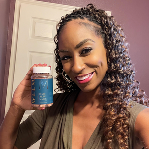Person smiling and holding a bottle of hair, skin, and nails vitamins.